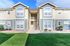 Charming multi-family apartment exterior with elegant two-tone siding, large windows, and vibrant green landscaping.