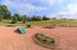 Expansive outdoor dog park with agility equipment, surrounded by lush greenery and a serene landscape.