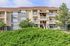 Charming multi-story apartment building with elegant balconies, surrounded by lush greenery and blue skies.