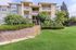 Charming apartment building with lush greenery, featuring a serene entrance and inviting balconies.