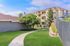 Charming apartment complex with lush green landscaping, inviting walking paths, and modern multi-level buildings under a serene blue sky.