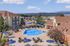 Inviting apartment complex with sparkling outdoor pool, surrounded by sun loungers and elegant seating areas, offering a tranquil escape and scenic views.