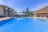 Inviting outdoor pool area with modern lounge chairs and vibrant sun shades, perfect for relaxation.