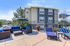 Inviting outdoor patio with stylish blue-striped seating, sun loungers, and vibrant flower arrangements, perfect for relaxation in a modern apartment setting.