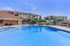 Luxurious apartment complex with a sparkling blue swimming pool, surrounded by lush greenery and stylish lounging areas.