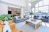 Bright and airy living room with floor-to-ceiling windows, modern gray sofas, and a sleek wooden coffee table, creating a welcoming and stylish atmosphere.