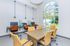 Bright office space with large arched window, modern wood table, vibrant yellow chairs, and sleek workstations offering a productive environment.