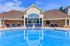 Luxurious outdoor swimming pool area with comfortable lounge chairs and elegant clubhouse backdrop under a clear blue sky.