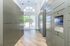Bright and modern package delivery room with sleek lockers and electronic keypads, featuring elegant wooden flooring and a large arched glass window.