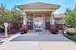 Elegant entrance of a modern apartment complex featuring lush landscaping and stylish architecture.