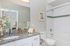 Elegant bathroom featuring a granite countertop, modern fixtures, and a spacious tub with clean white tiles.