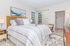 Inviting bedroom with stylish striped bedding, cozy accent pillows, and elegant decor, featuring a generous walk-in closet and soft natural light from large windows.