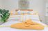 Cozy bedroom with bright yellow and white bedding, decorative pillows, and lush green plants, creating a warm and inviting ambiance.