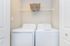Modern laundry room with sleek washer and dryer set, featuring a convenient overhead storage shelf with a stylish woven basket.