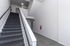 Modern apartment stairway with sleek railing, soft carpeting, and bright natural lighting, highlighting clean design and spacious layout.