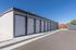 Modern self-storage facility with multiple secure, roll-up doors under a clear blue sky.
