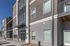 Modern apartment exterior with sleek grey design, large windows, and inviting balconies under a clear blue sky.