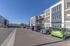 Modern apartment complex with ample parking, featuring contemporary architecture and spacious balconies set against clear blue skies.