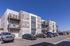 Elegant modern apartment building with spacious balconies and ample parking under a clear blue sky.