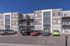 Modern three-story apartment building with a sleek design, ample balconies, and convenient parking.