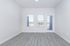 Bright and airy apartment room with sleek laminate flooring and large windows leading to a charming balcony view.