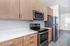 Modern kitchen with sleek stainless steel appliances, elegant wooden cabinetry, and bright natural light through a large window.