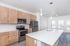 Modern kitchen with sleek stainless steel appliances, elegant wood cabinetry, and a spacious white island for culinary creativity.