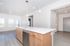 Bright and modern kitchen featuring sleek white countertops, pendant lighting, and spacious wooden cabinetry in an open-concept layout.