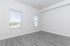 Bright and airy room featuring modern laminate flooring, two large windows with blinds, and fresh white walls.