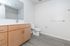 Sleek and modern bathroom with elegant wooden cabinetry, spacious mirror, and minimalist design.