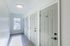 Bright hallway with modern white doors, sleek flooring, and natural light streaming through a window.