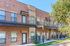 Charming brick apartment complex with private balconies, nestled in a lush, green setting.