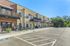 Modern apartment complex with private balconies and ample parking under a clear blue sky.