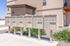 Modern apartment complex exterior featuring organized mailboxes, surrounded by well-maintained landscaping under clear blue skies.
