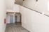 Bright modern hallway with sleek flooring and stylish lighting, featuring multiple doors and a wide staircase.