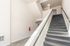 Modern apartment staircase with plush carpeting leading to a welcoming entrance, complemented by sleek white walls and contemporary lighting.