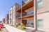 Modern apartment building exterior featuring spacious balconies and tasteful landscaping under a clear blue sky.