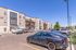 Modern apartment complex with contemporary design, ample parking, and a vibrant atmosphere under a clear blue sky.