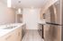 Modern kitchen with sleek stainless steel appliances, elegant pendant lighting, and stylish wood cabinetry on light hardwood floors.