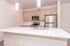 Modern kitchen with sleek stainless steel appliances, elegant light wood cabinetry, and a spacious white quartz island.