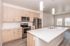 Contemporary kitchen with sleek stainless steel appliances, light wood cabinetry, and a spacious white island under modern pendant lighting, offering a bright and inviting cooking space.