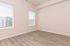 Bright and inviting room with sleek hardwood flooring and ample natural light from large windows, perfect for a cozy living space.