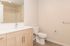 Bright and modern bathroom featuring elegant wood cabinetry, a large mirror, and sleek fixtures.