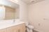 Modern bathroom with sleek design featuring a spacious vanity, large mirror, and pristine white fixtures.