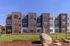 Modern apartment complex with stylish facade, lush green lawn, and neat landscaping under a clear blue sky.