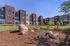 Modern apartment complex with vibrant landscaping, featuring lush green grass and decorative rocks under a bright blue sky.