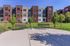 Modern apartment complex with three-story buildings, lush green landscaping, and inviting outdoor seating area.