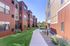 Charming modern apartment complex with vibrant architecture, lush green landscaping, and a welcoming walkway.