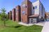 Modern apartment complex with sleek design, lush green lawn, and clear blue sky offering an inviting living environment.