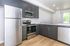 Sleek modern kitchen featuring stainless steel appliances, dark wood cabinetry, and a bright, open layout.
